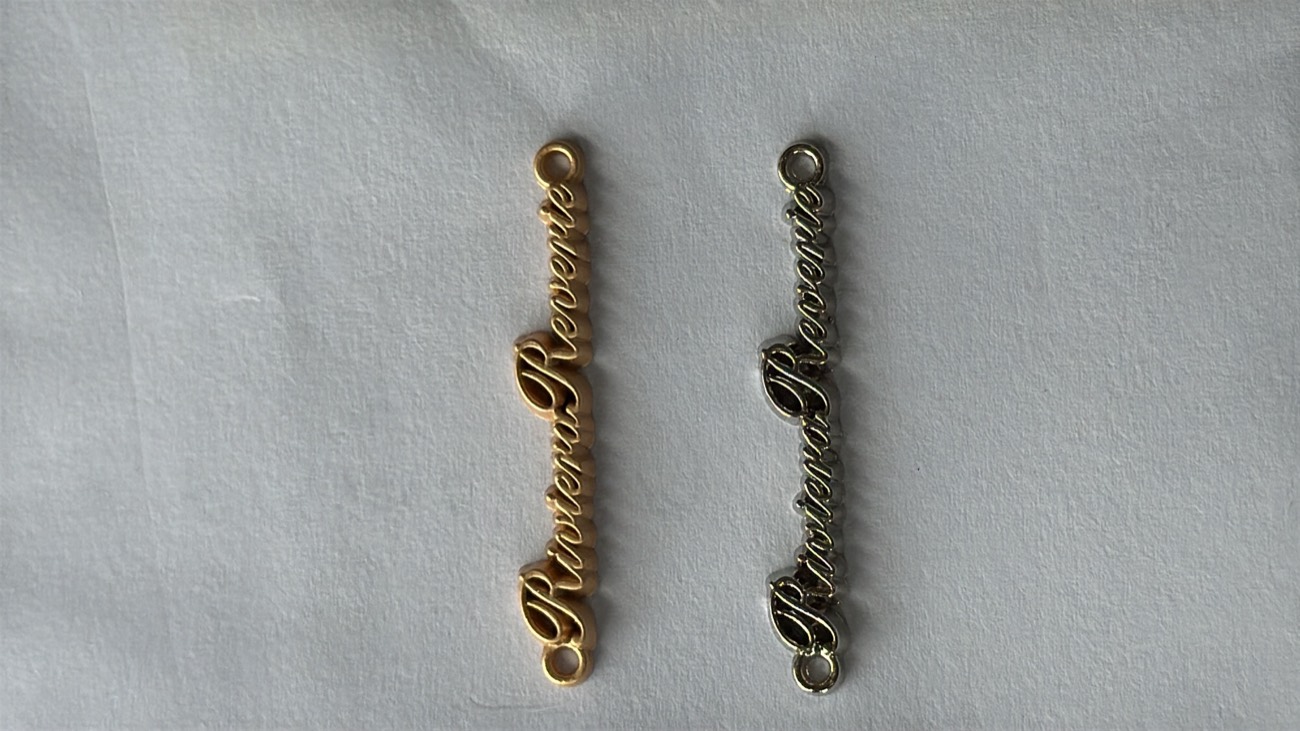 Two Riviera Reverie script plates, one gold and one silver