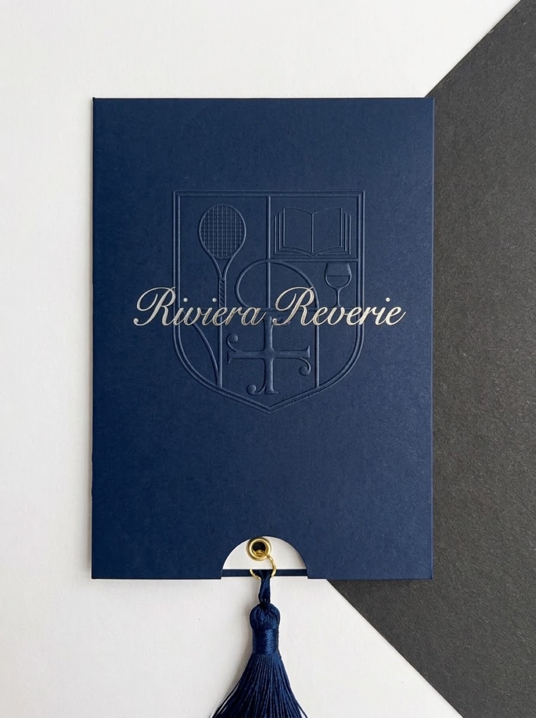 Navy gift sleeve embossed with the Riviera Reverie crest and the name in silver script